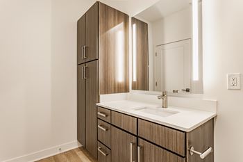 A bathroom with a sink, mirror, and wooden cabinets.